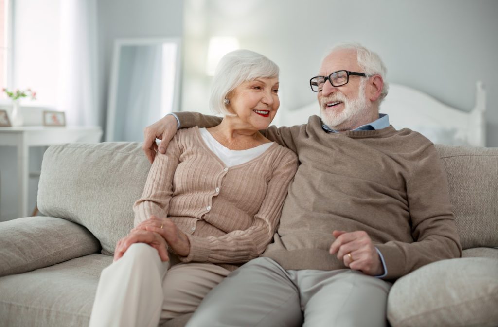 Happy senior couple in independent living community sitting together on couch