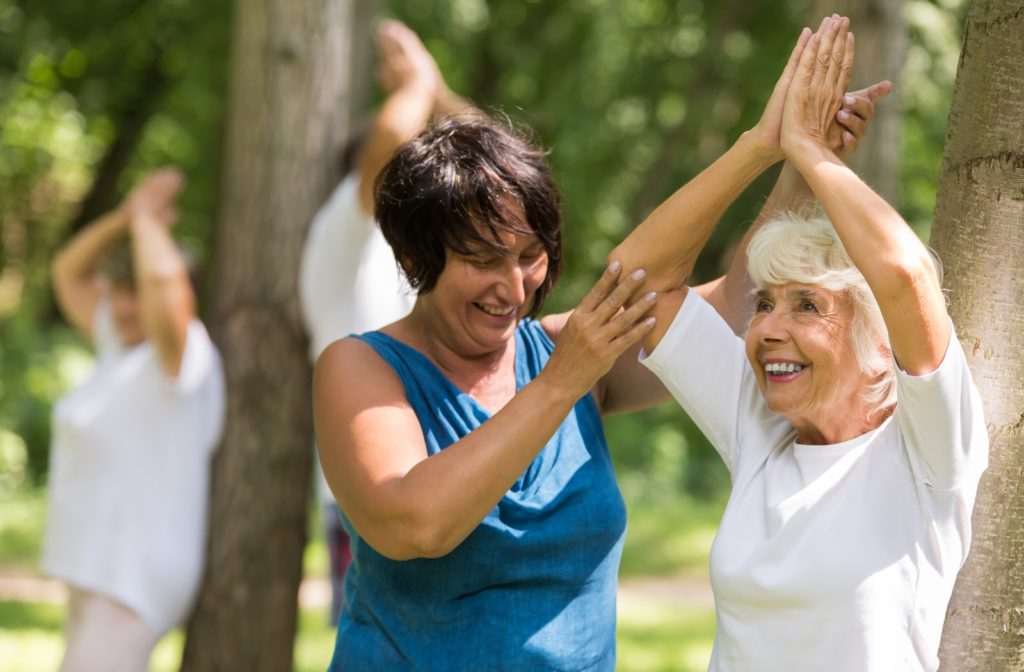 Happy senior women getting help from instructor during yoga session at senior community