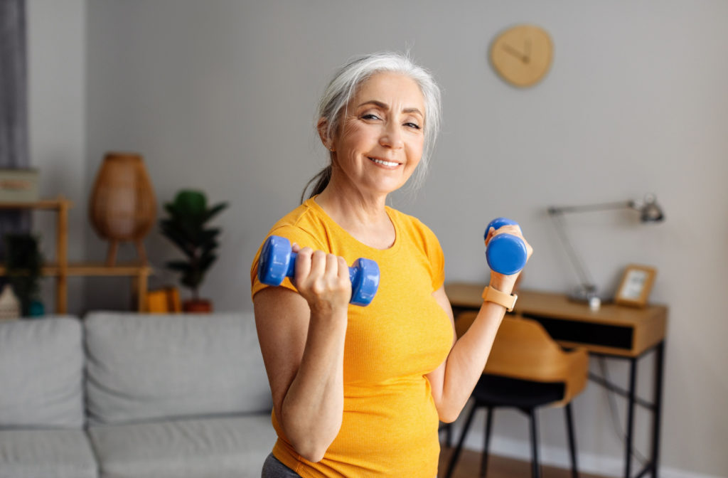 A smiling senior woman exercising with dumbbells.