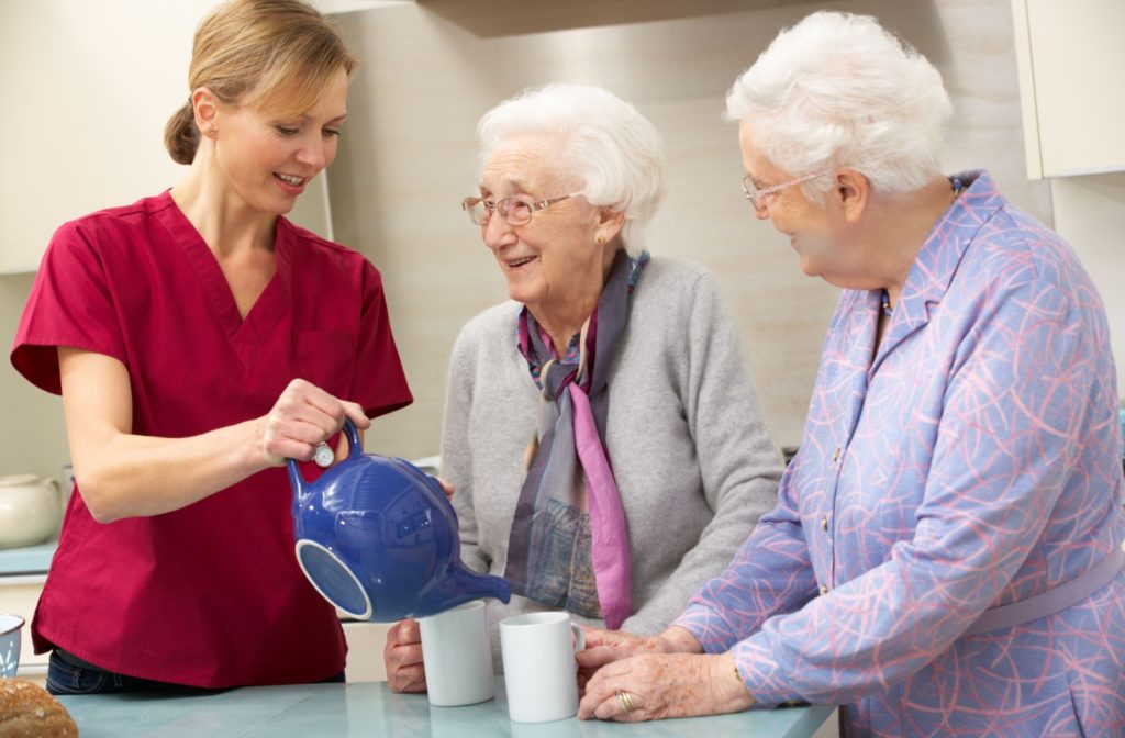 Nurse pouring tea for two female residents.