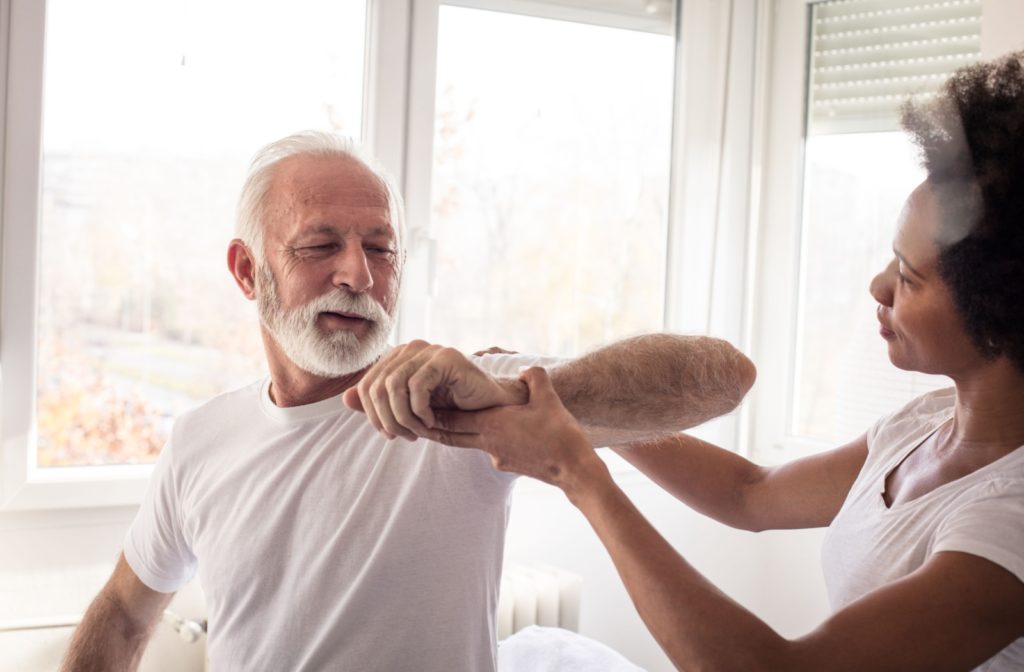 A senior patient and an adult physical therapist.