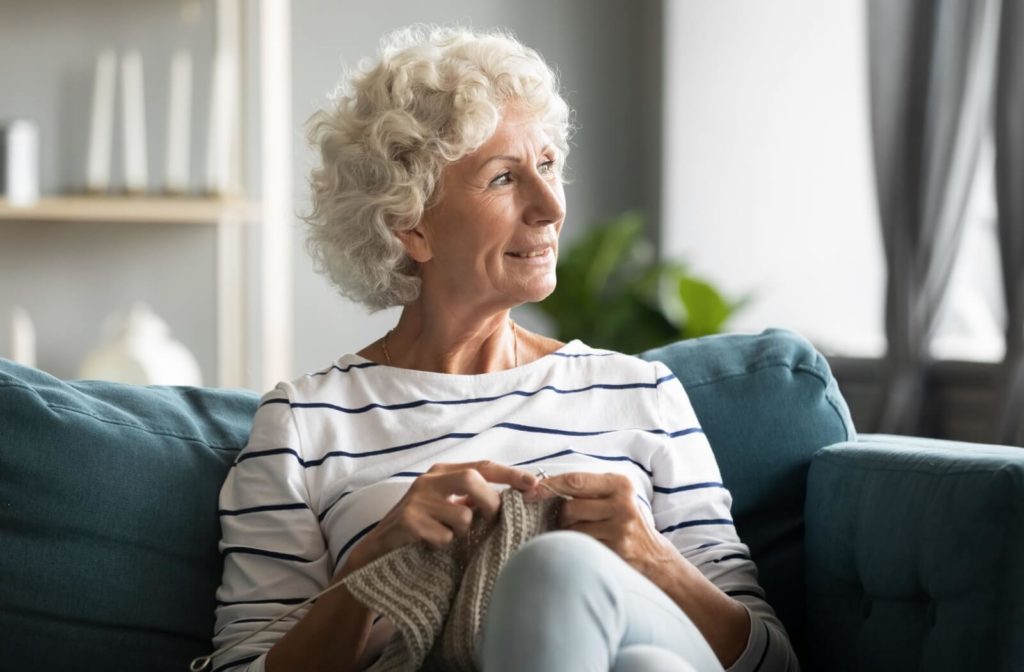 A senior woman enjoying knitting on her couch at an assisted living community.