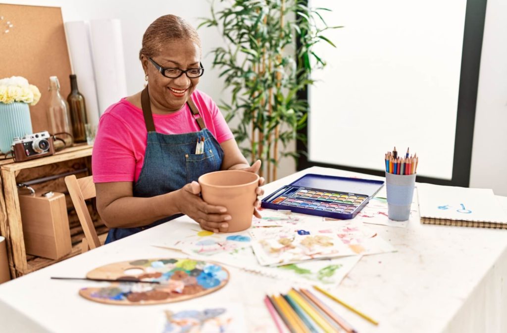 A senior woman getting ready to paint a new plant pot to decorate her home at an assisted living community.