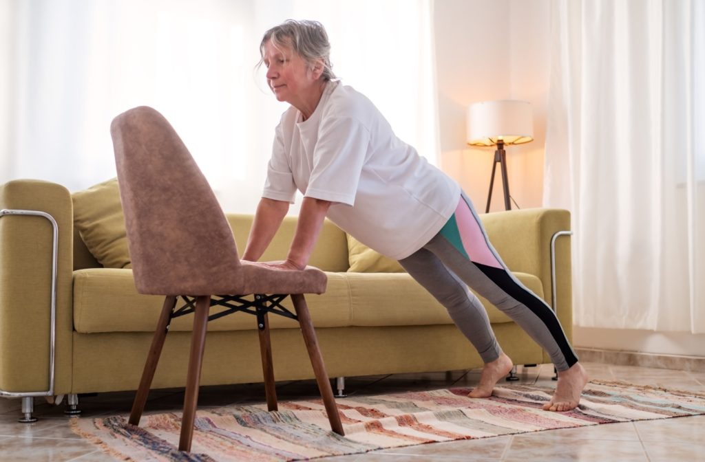 A senior doing a push up on a chair yoga during their routine.