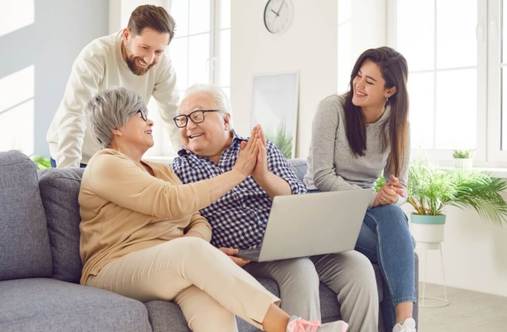 Adult children laughing as their older parents high-five while researching local assisted living communities.