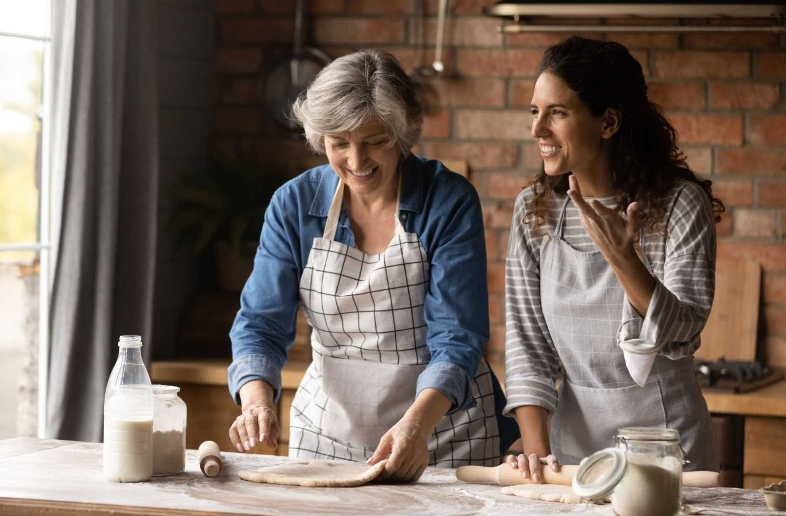 A woman making cookies with her senior mother in a kitchen.