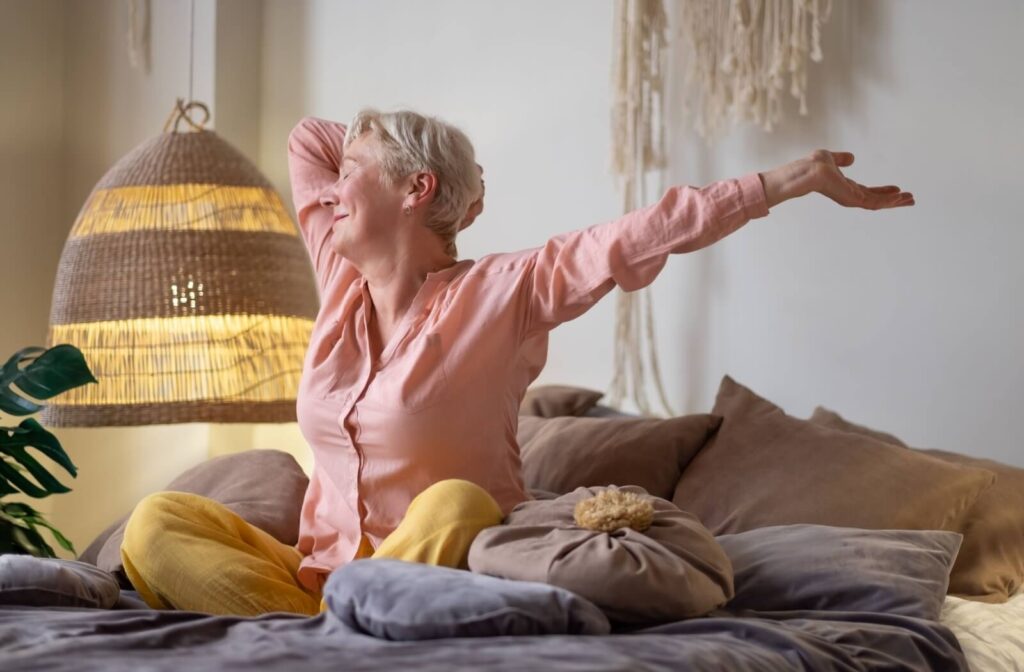 An older adult stretching in bed with a smile as they prepare to start their day.