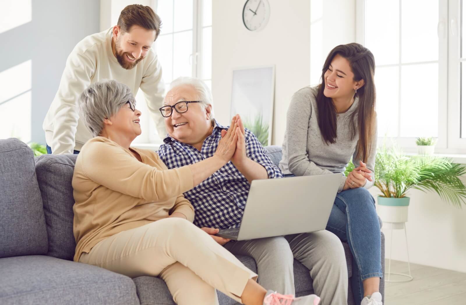 Adult children laughing as their older parents high-five while researching local assisted living communities.